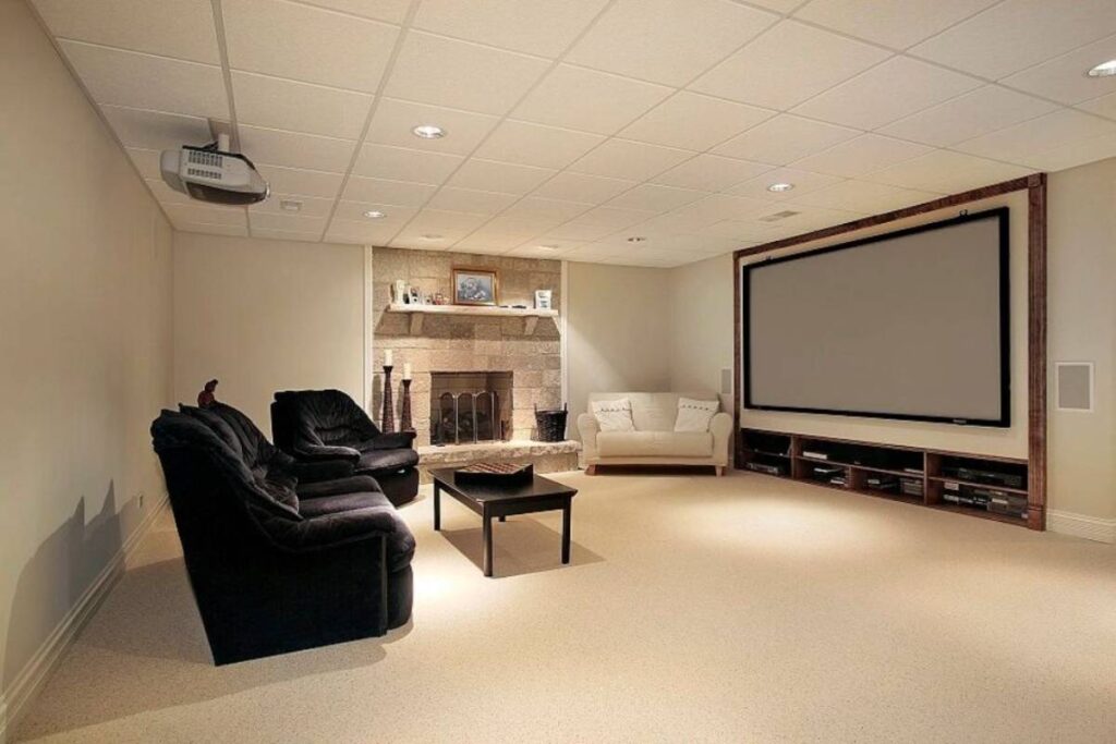 A modern home theater room with large screen, plush seating, and a stone fireplace.