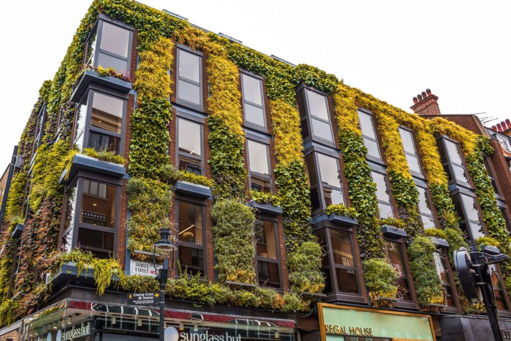 A building facade densely covered with green and yellow vertical gardens