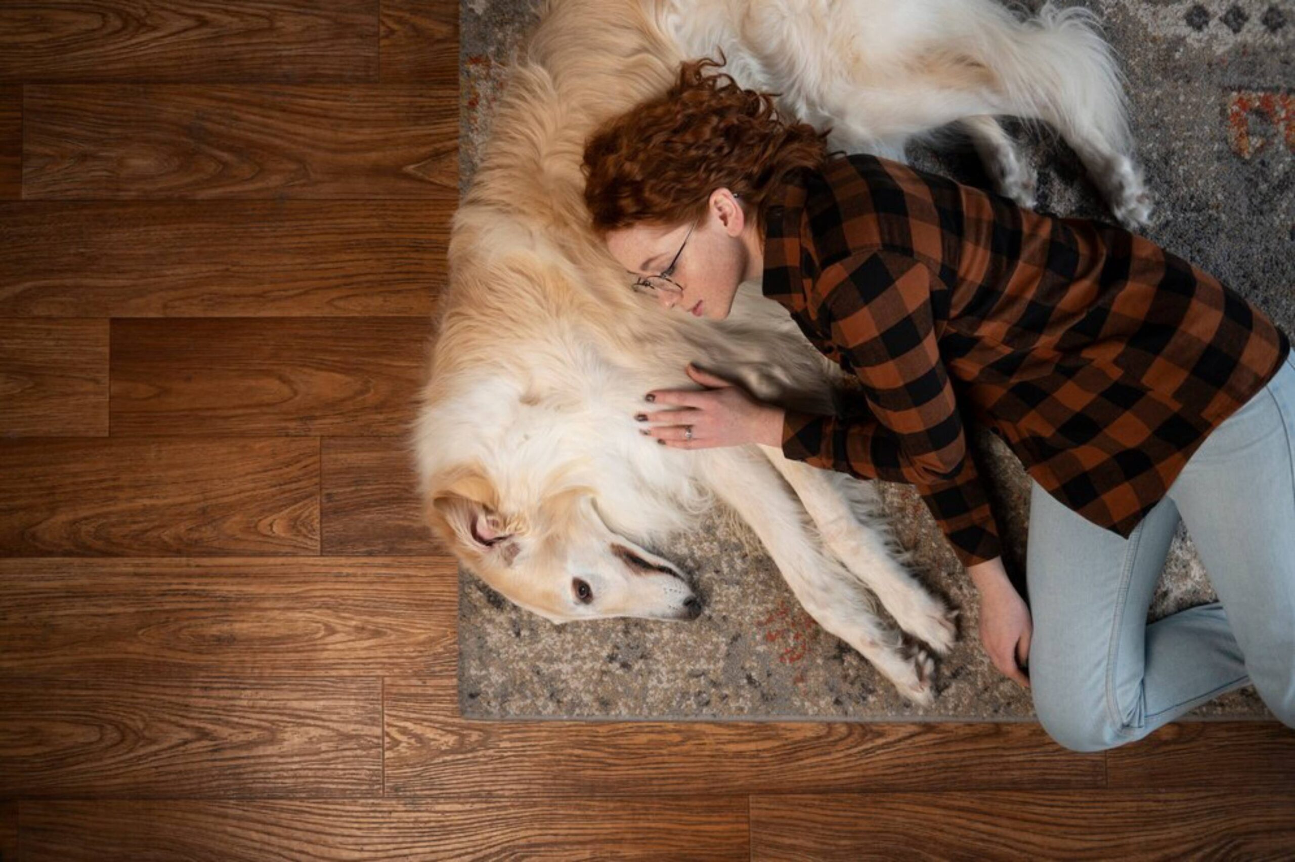 A couple unrolling a carpet in a new home surrounded by moving boxes.